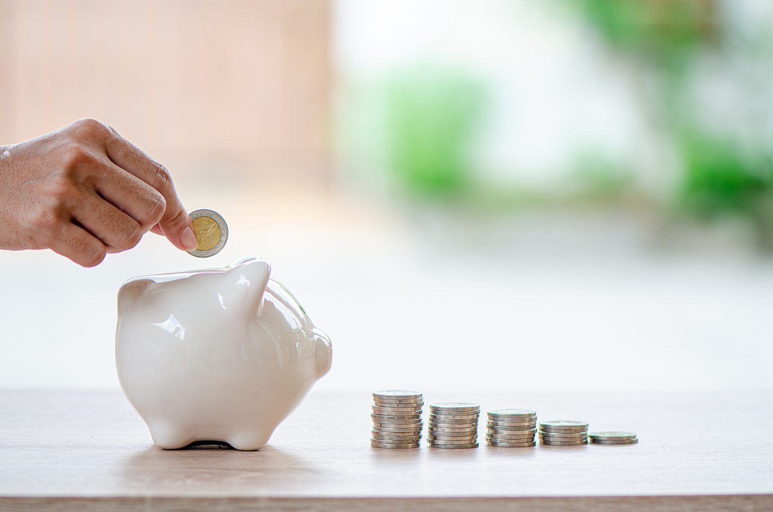 hand of man drop coin into piggy bank arranged as graph
